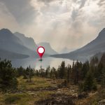 A lonely island in the middle of a beautiful forest lake. A map pin location icon hovers above it.