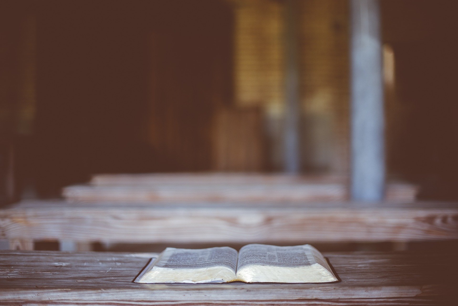 An image of a Bible, laying open on a table in an empty room.